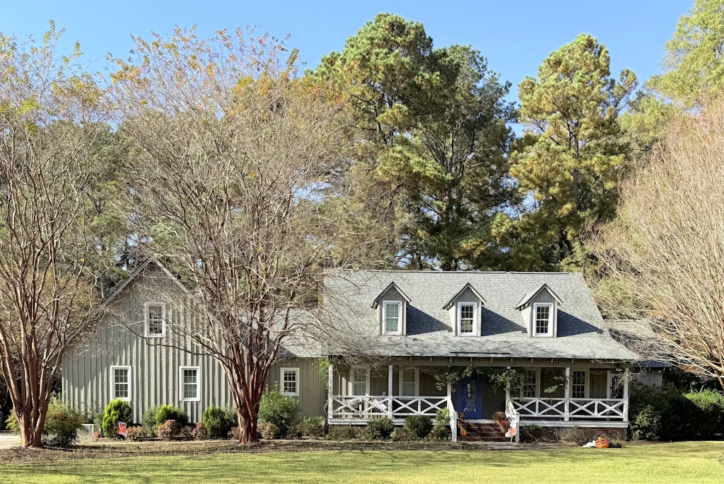 A picturesque ranch-style house surrounded by autumn trees and greenery.