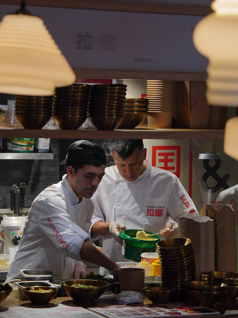 Chefs in a Japanese restaurant kitchen preparing dishes with focus and precision.