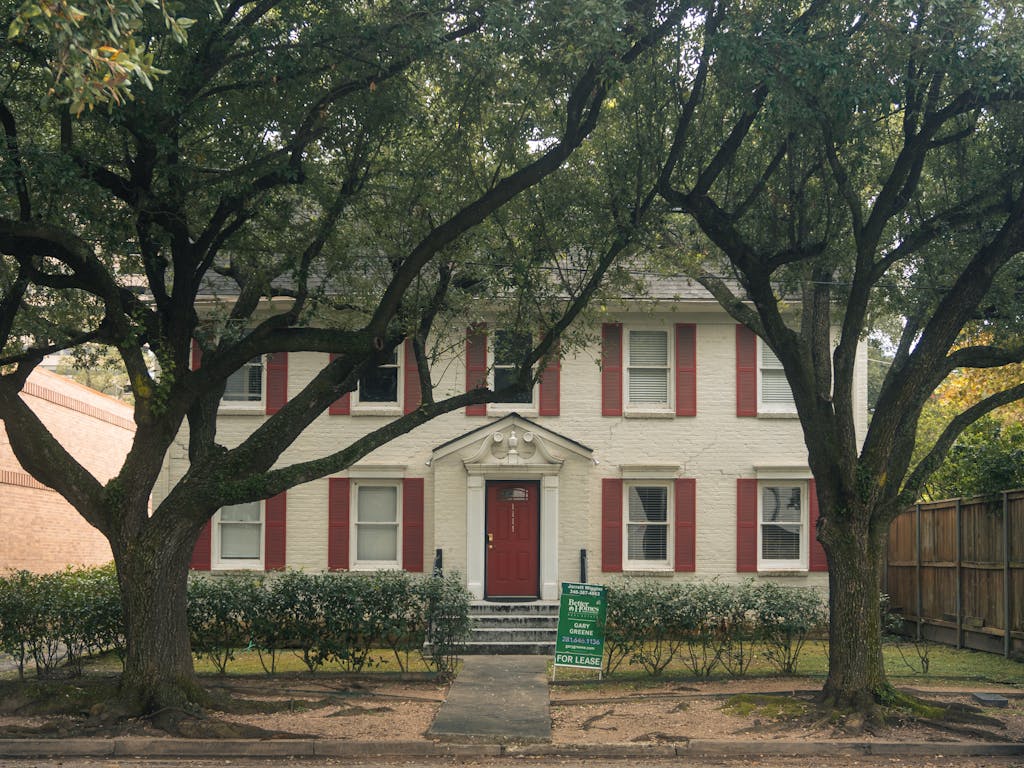 Classic colonial house with red shutters and trees in Houston, Texas, available for lease.